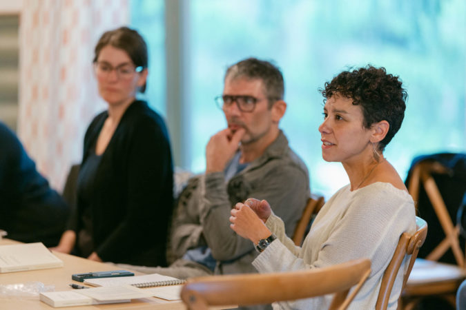 Phoebe Cohen, Jason Livingston, and Caroline Doherty sitting by a table at a retreat hosted by the Simons Foundation in September 2023. Phoebe Cohen is speaking.