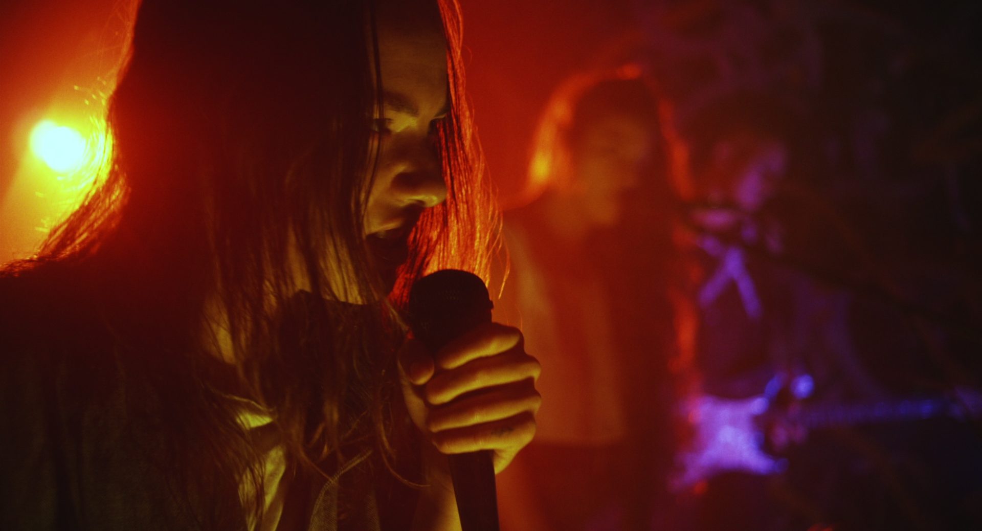 A still from EMPTY METAL. A person with gritted teeth, singing into a microphone.