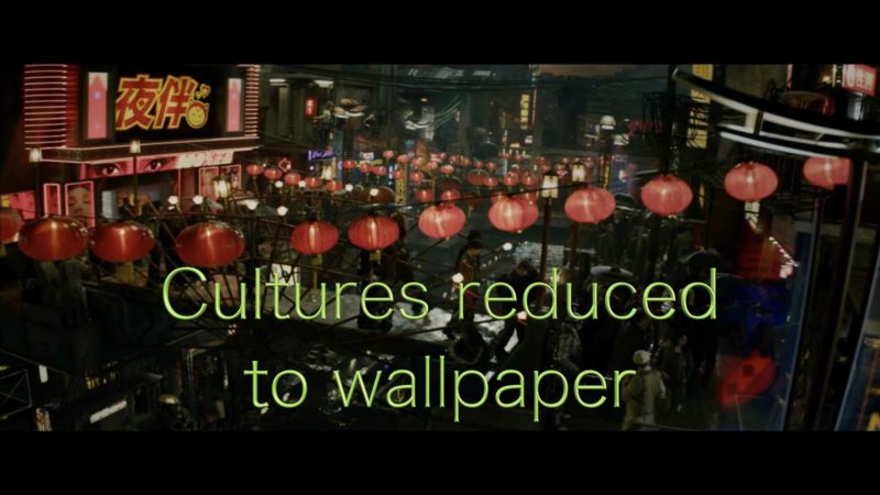 A still from On the Neon Horizon by Astria Suparak. "Cultured reduced to wallpaper," in acid-green font over a photo of a street with dozens of hanging red paper lanterns.