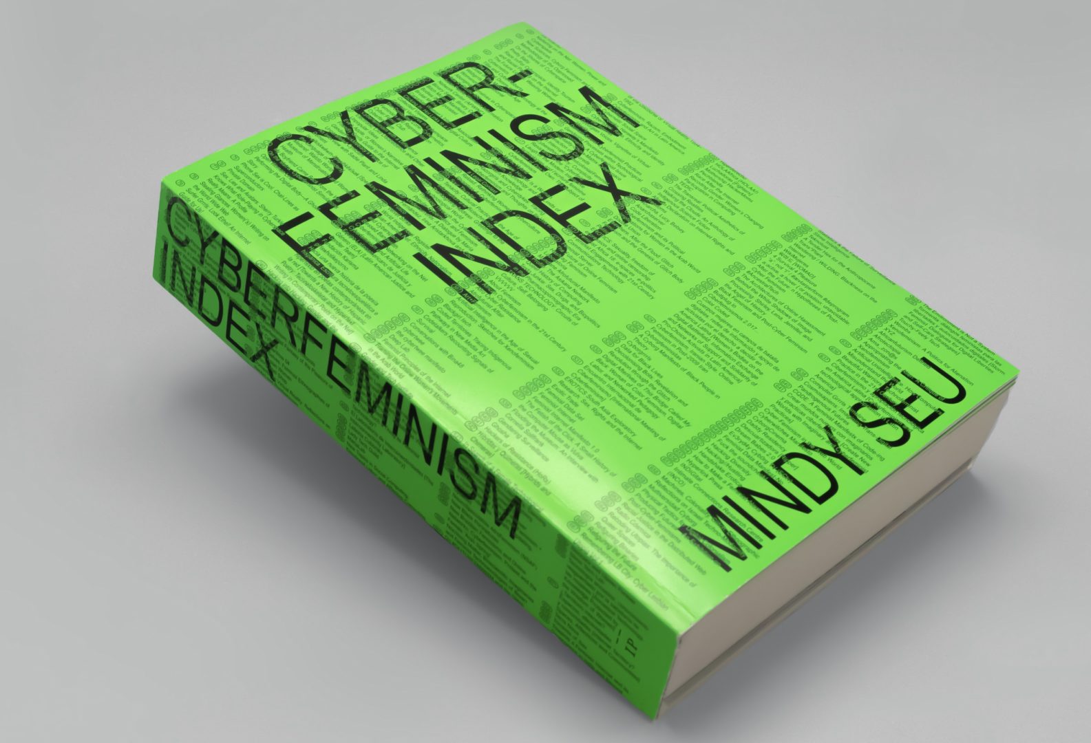 A photograph of a thick green book with the title "Cyberfeminism Index" by Mindy Seu.