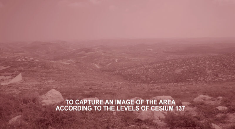 Still of Inas Halabi, We Have Always Known the Wind’s Direction (2019). A red and pink tinted filtered image of a Palestinian landscape with white subtitles. The subtitles state "TO CAPTURE AN IMAGE OF THE AREA ACCORDING TO THE LEVELS OF CESIUM 137".