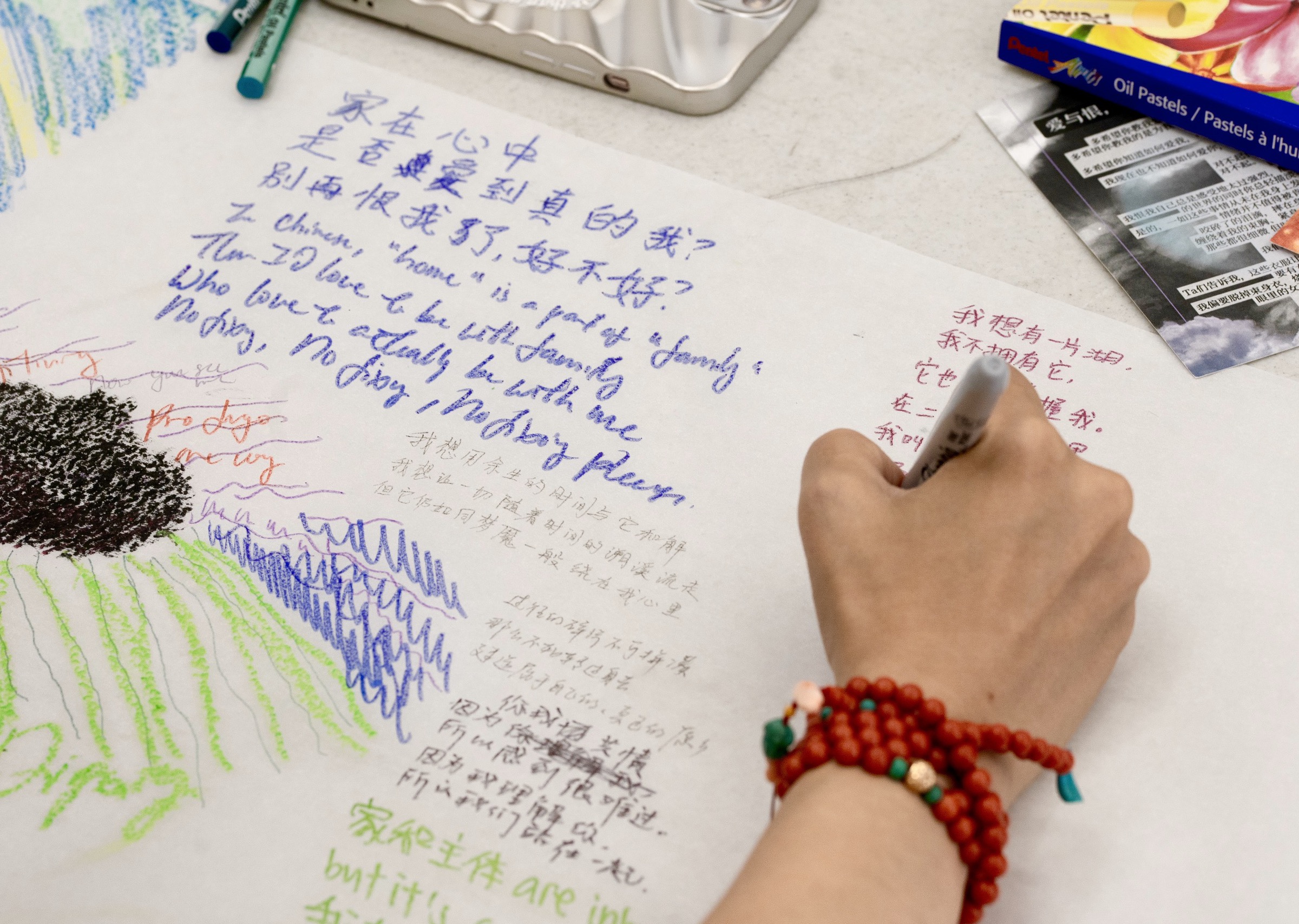 Colorful handwriting in blue, green, orange, and black in both Chinese and English. Someone with a red bracelet is seen writing on white rice paper.
